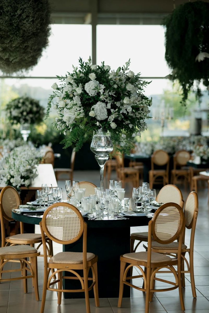 A reception table with white floral centerpieces and wooden chairs